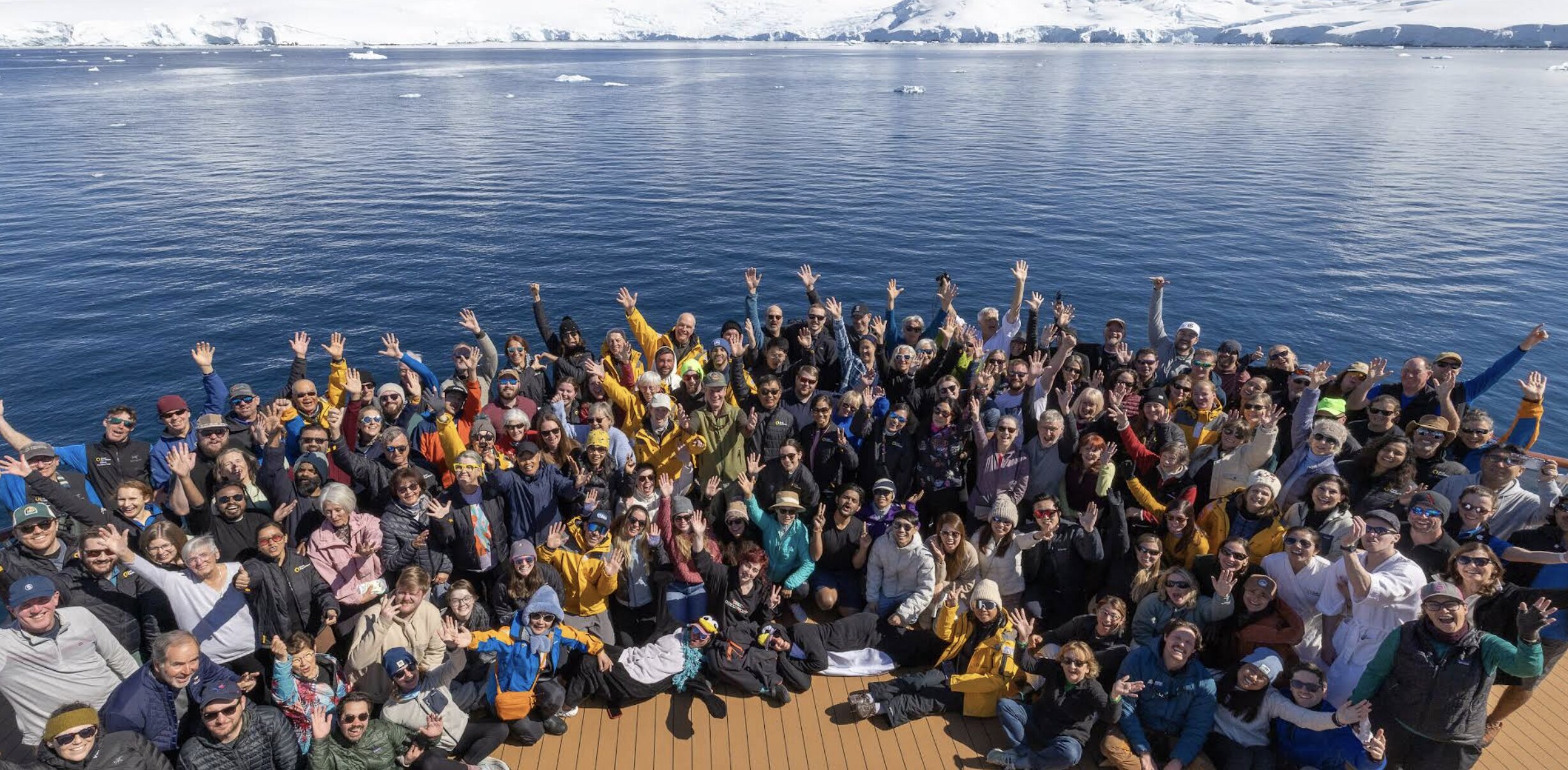 Expedition guests in yellow parkas gather for a group photo on a Quark Antarctica Peninsula voyage
