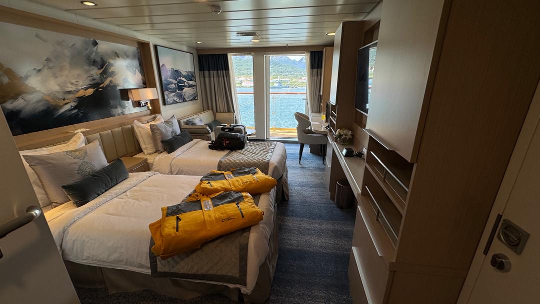 A Quark expedition ship cabin with parkas laid out, overlooking Ushuaia harbour