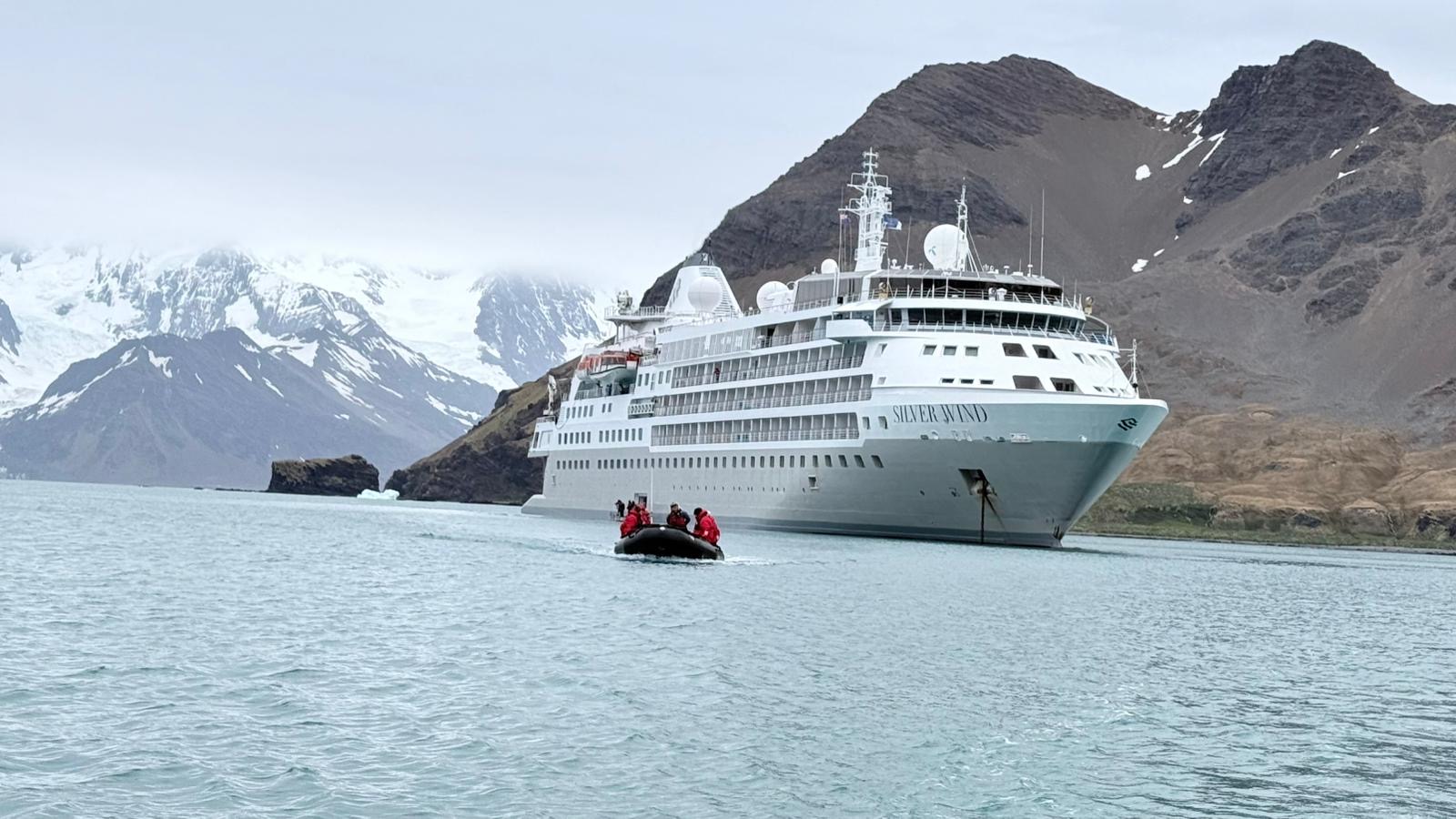 A Silversea expedition ship and zodiac anchored in a calm Antarctic bay